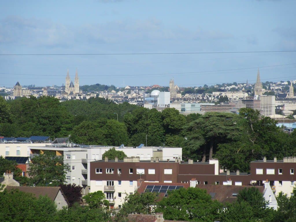Les toits de Caen et les flèches de ses églises, entre les arbres.