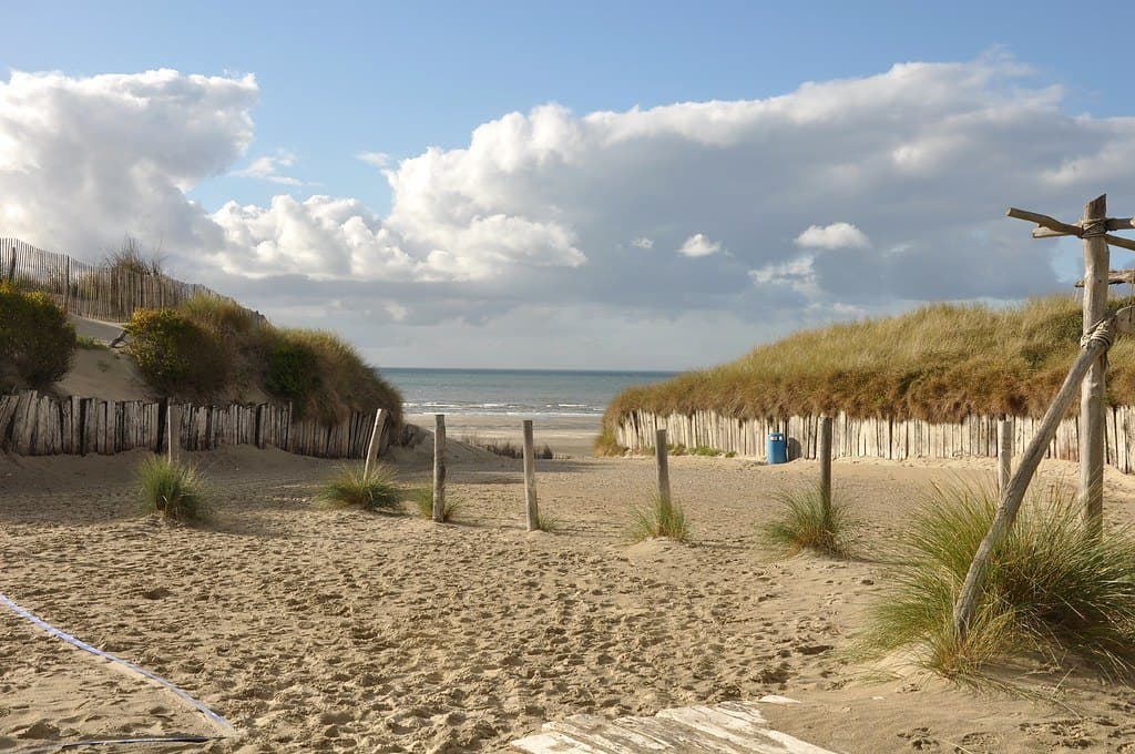 Les dunes et la plage d'une côte normande sous un ciel nuageux.