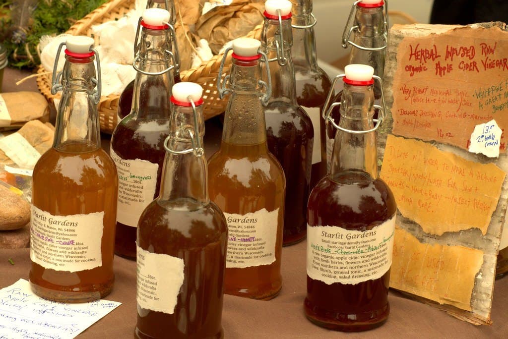 Des bouteilles de cidre artisanal aux étiquettes manuscrites, alignées sur une table.